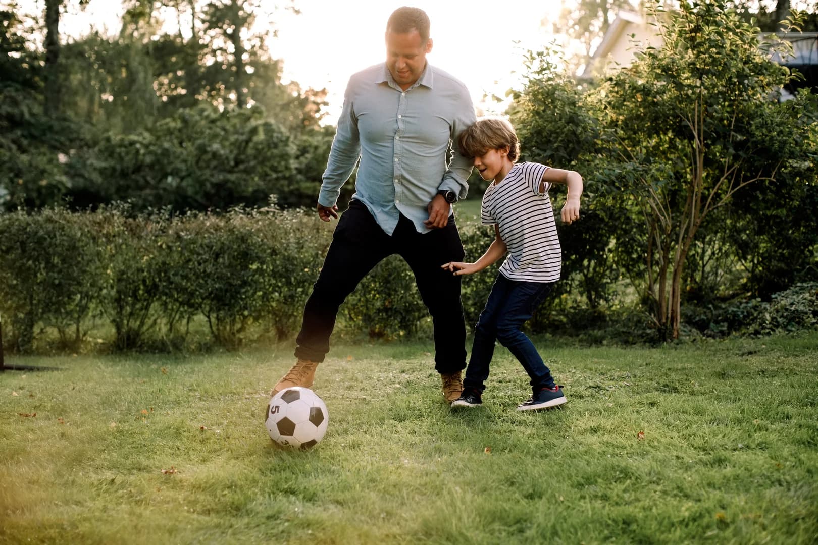 Father and son playing soccer outdoors