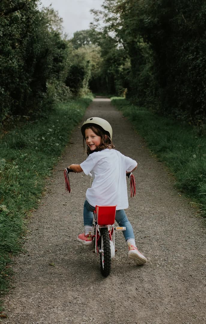 139763 Young Girl on Bike Down a Lush Path USP Crop