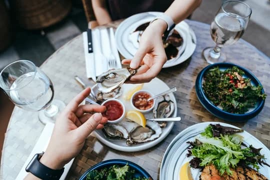 Dining Scene Aerial of Hands Passing Oyster