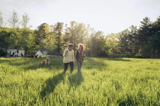 Women and Dog Walking Through Field