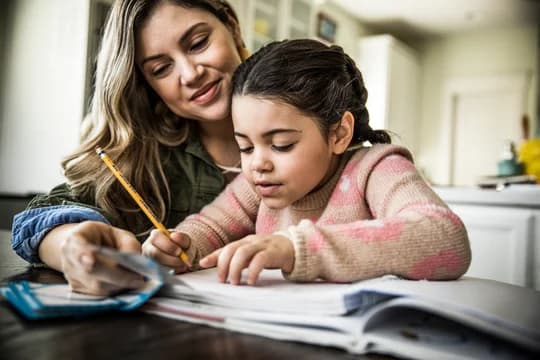 Young girl and mother working on homework for school