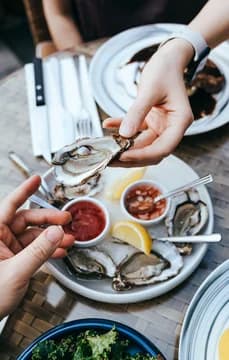 139778 Dining Scene Aerial of Hands Passing Oyster USP Crop